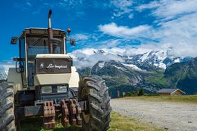 the tractor stands near the road against the background of mountains