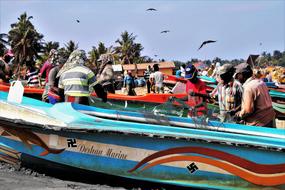 people at painted boats on Beach near Fishing Village