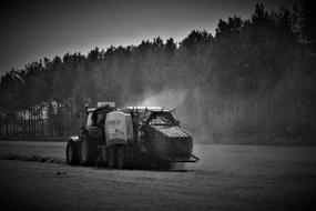 Black and white photo of the John Deere 7430 tractor on the field near the trees