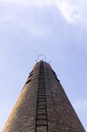 industrial brick chimney with ladder at sky