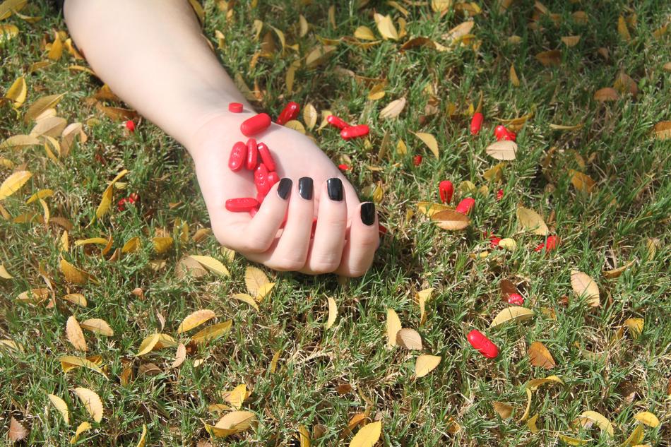 red capsules in hand for suicide