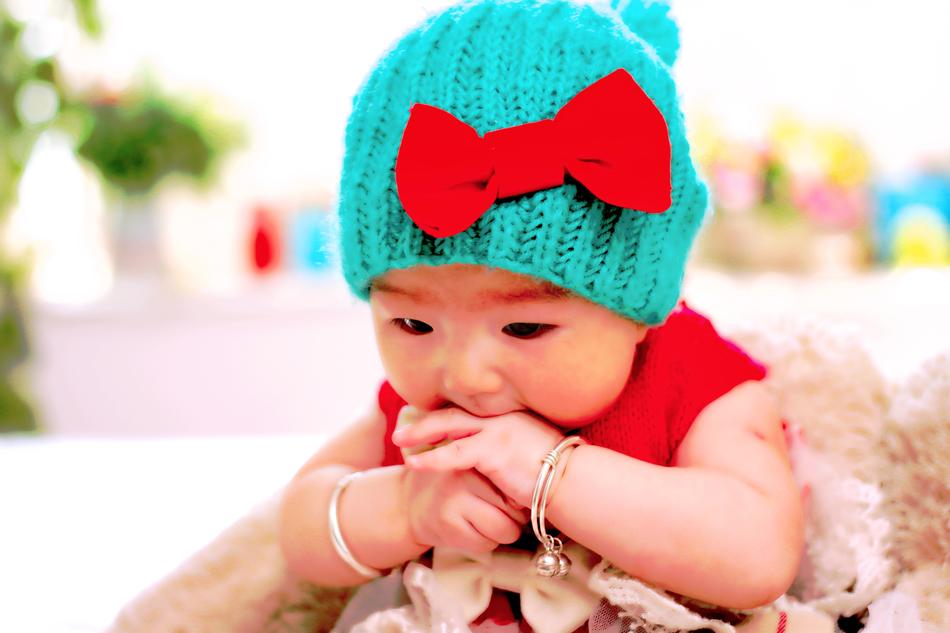 baby in a turquoise hat with a red bow