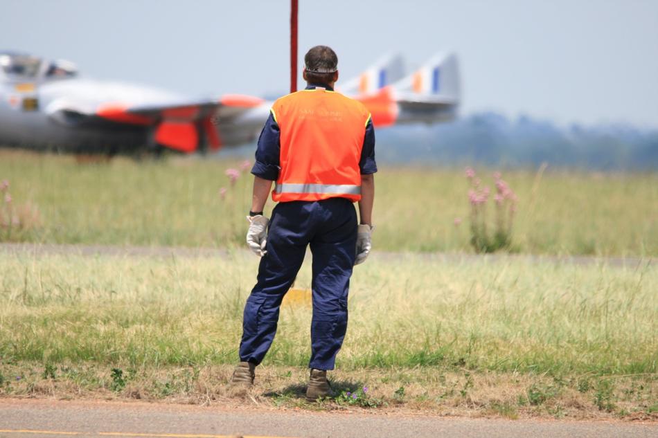 Back view of the crew member, near the colorful vampire jet, on the colorful field
