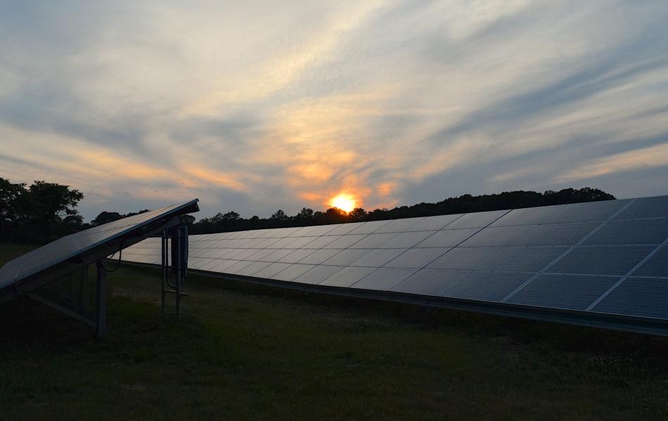 sunset over solar panels among nature