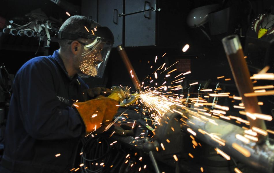 Worker in the mask, working with metal, with the sparks