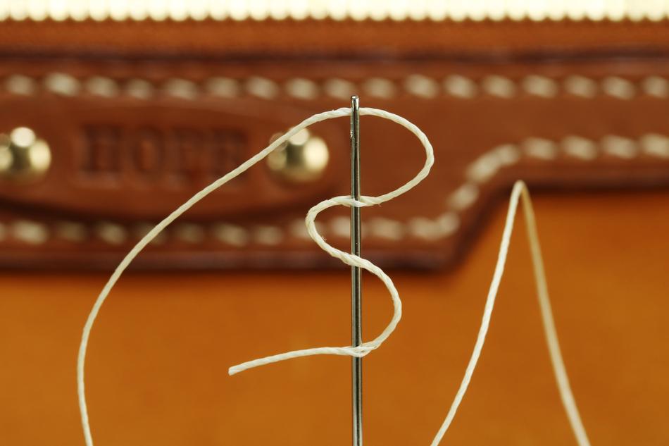 Close-up of the needle, with the tread, for the leather craft