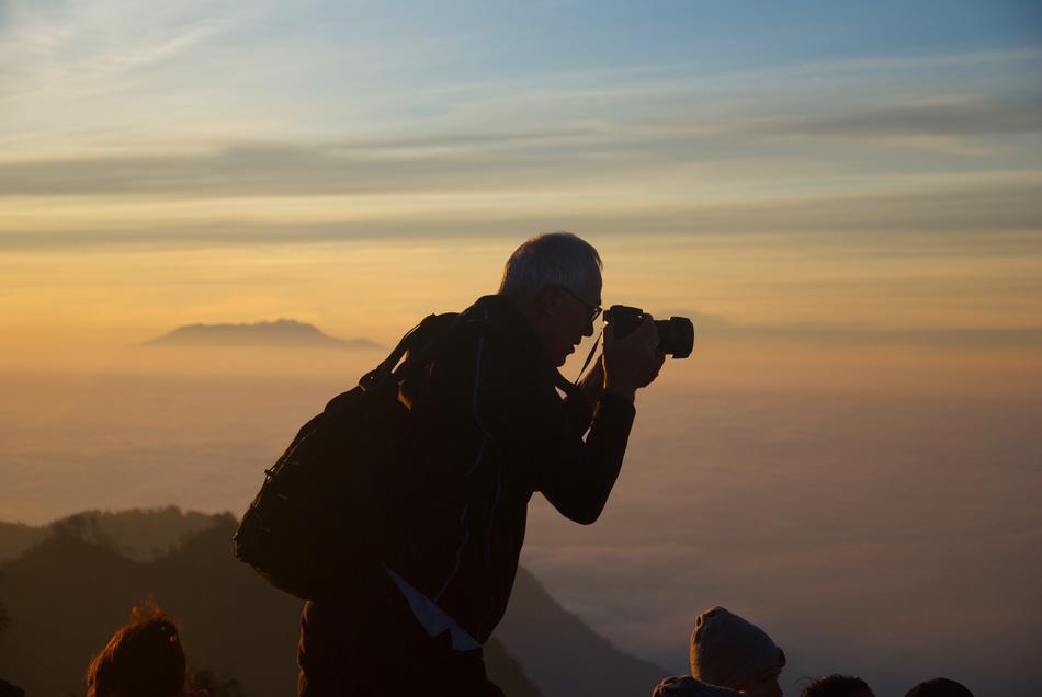 Man with Camera on top of the mountain at dusk