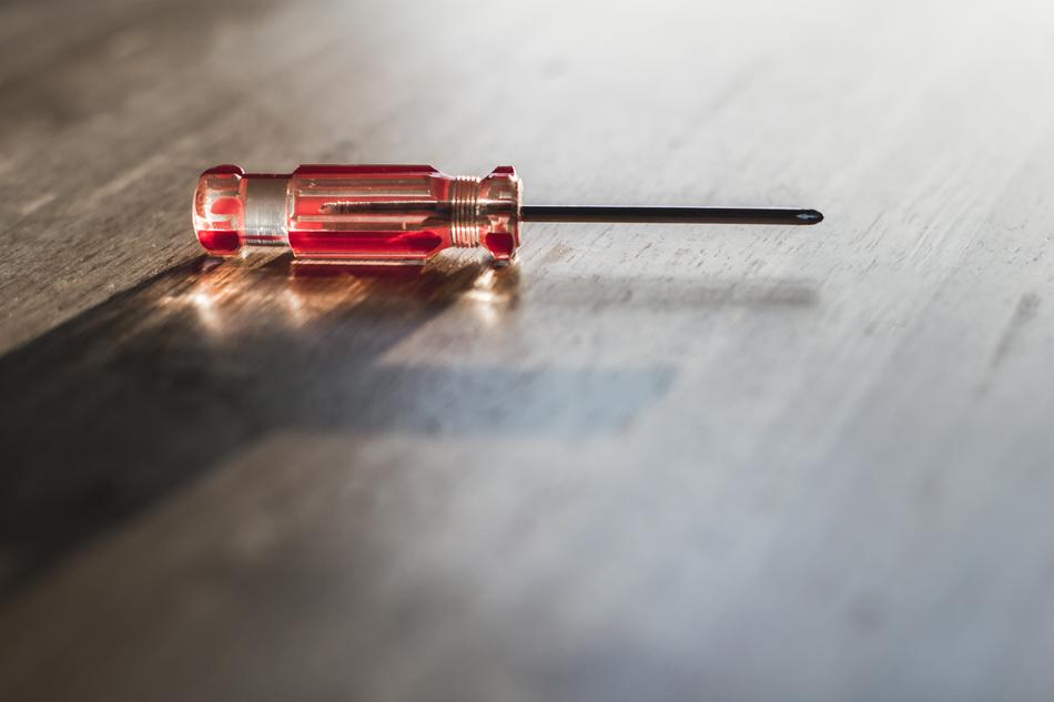 Red transparent screwdriver on the wooden surface