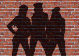 three female silhouettes, shadow on brick wall