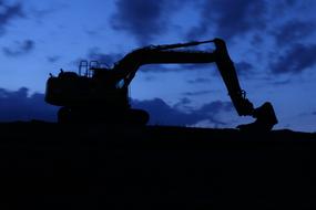 black silhouette of an excavator at a construction site