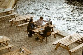 three man resting in open air cafe on embankment