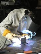 Person in the protection and helmet, doing welding with the metal