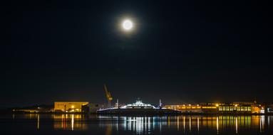 night photo of an industrial shipyard under the moon