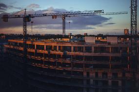 tower cranes beside of industrial building at dusk