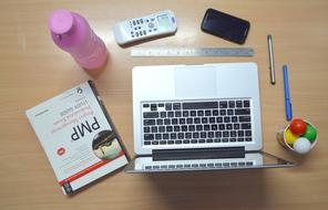 laptop, remote control, stationery, bottle of water on the table