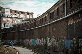 man walks on rails along an industrial building