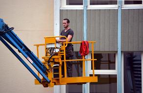 worker on a gondola on the facade of a house