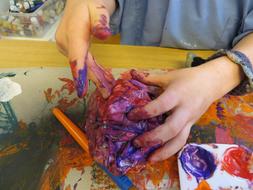 Child painting with colorful paints on hands
