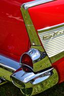 Close-up of the beautiful, classic, retro, red and metallic Chevrolet car on the green meadow