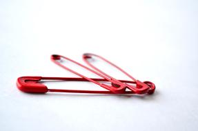 Beautiful, red safety pins, on the white surface