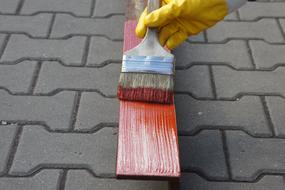 a man painting a wooden plank on the street