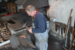 blacksmith works with metal near the anvil