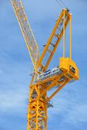 Yellow crane machine, at blue sky, with white clouds