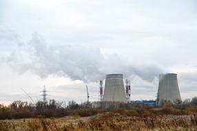 Landscape of the industrial plant with smog, among the colorful fields, under the cloudy sky