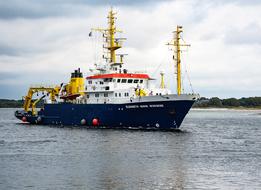 Colorful working ship in the Baltic Sea, with the ripple, under the cloudy sky
