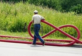 worker with a long red hose in nature