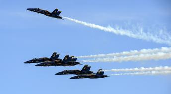 Flying "Blue Angels" airplanes, with white contrails, in the blue sky