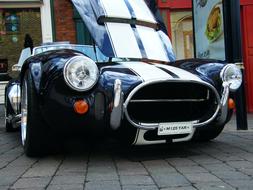 Beautiful, shiny, vintage Cobra car, with the white lines, on the pavement