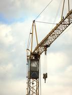 Close-up of the metal crane, with the cabin, at blue sky with clouds on background