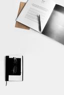 Open book with pen, notebook and eyeglasses, on the white table