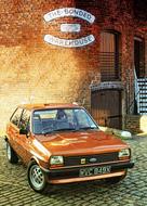 Shiny, orange Ford Fiesta Mk1, near the wall, in light