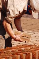 Man in cap, drying bricks in light