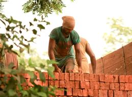 Indian workers, working with orange bricks