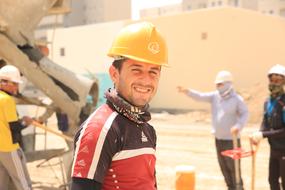 Smiling worker, among the others, in equipment, on the site