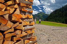 People, near the sawn timber wood, on the colorful and beautiful mountains, under the blue sky with white clouds