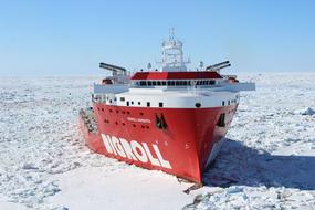 Red and white Bigroll Barentsz, among the beautiful, white ice, at blue sky on background