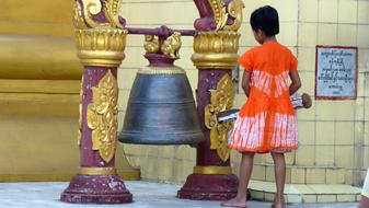 Girl, near the beautiful, colorful and decorated bell in Myanmar