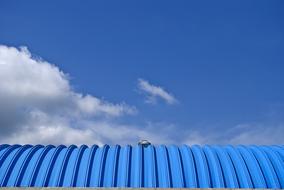 Blue industrial building, at beautiful blue sky with clouds on background