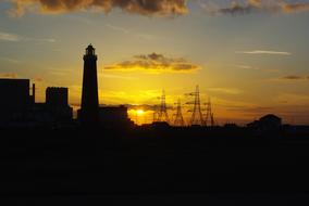 Black silhouettes of the lighthouse and Romney Marsh, in Dungeness, Ken, England, UK, at beautiful and colorful sunset
