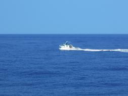 Small craft with waves in the beautiful, blue ocean, at blue sky on background