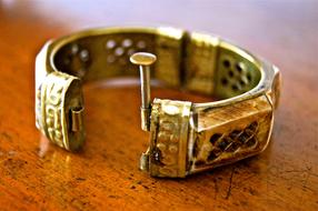 Close-up of the beautiful, shiny, gold, patterned jewellery, on the wooden table