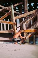 Guy, near the stairs of the wooden cottage, in light