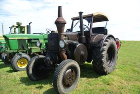 Colorful "Lanz Bulldog" tractor, on the green and yellow field, under the blue sky with white clouds