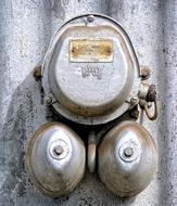 Close-up of the old, shiny bell, with the clamp, on the wall, in the light