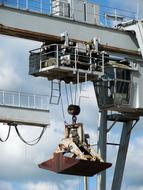 Close-up of the crane with the gripper, under the blue sky with white clouds