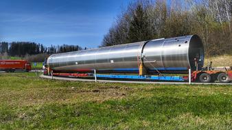 Shiny steel tank on the wheels, among the colorful plants